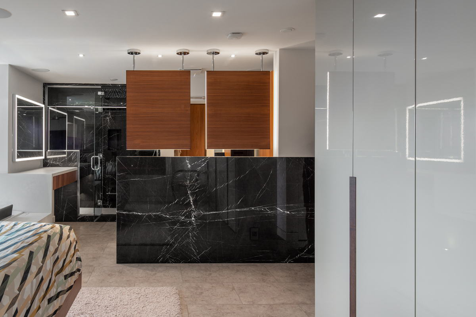 Master bedroom-bath connection with black marble divider wall