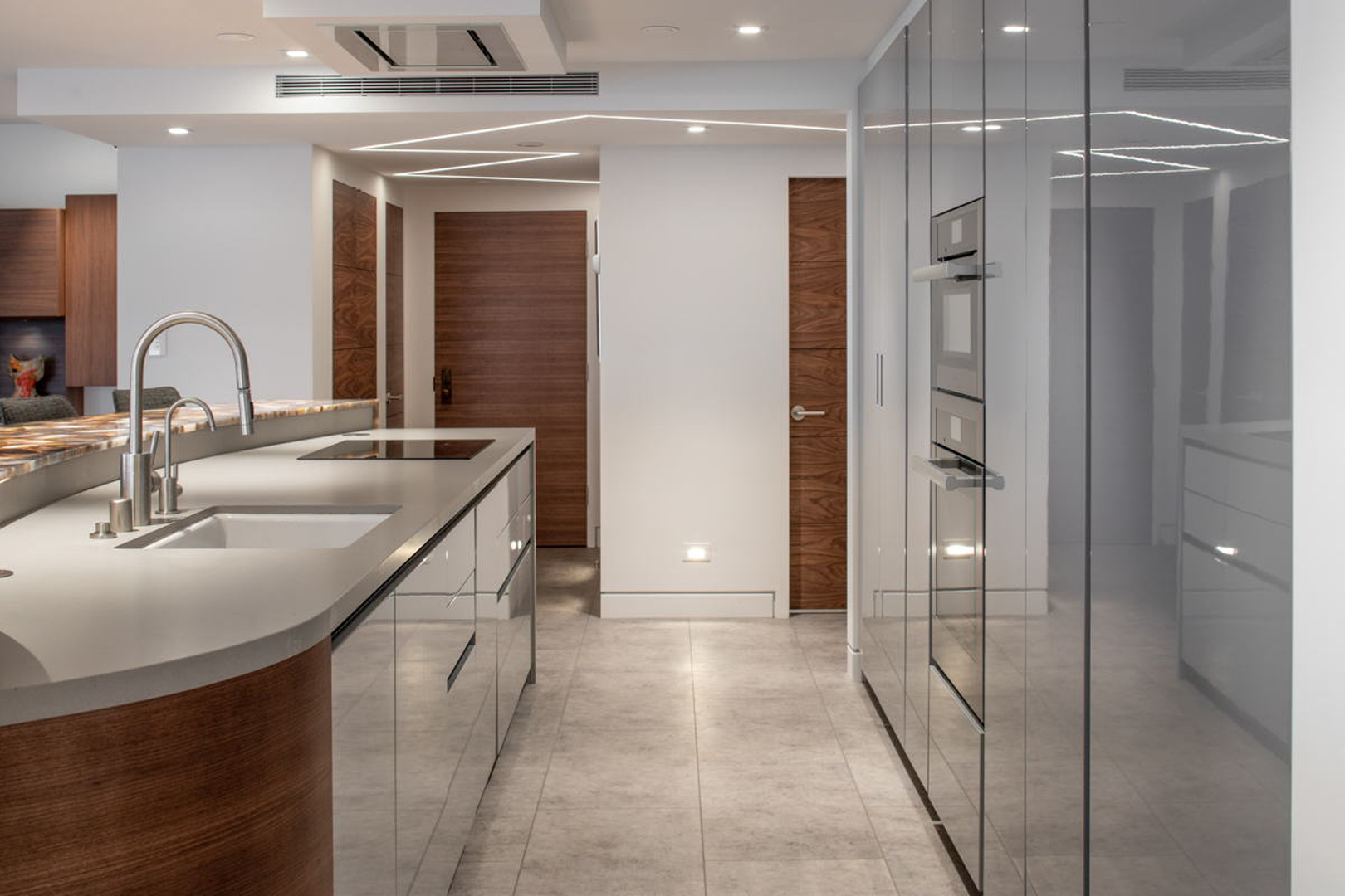 Kitchen with mirrored cabinetry, walnut accents, and integrated appliances