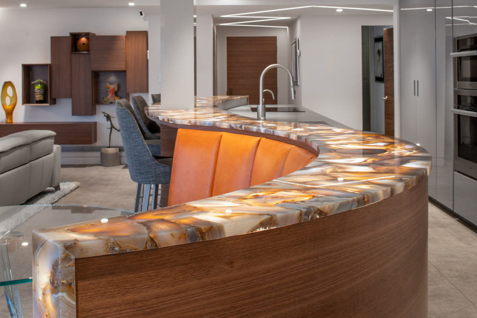 Curved backlit onyx countertop with amber glow and walnut base